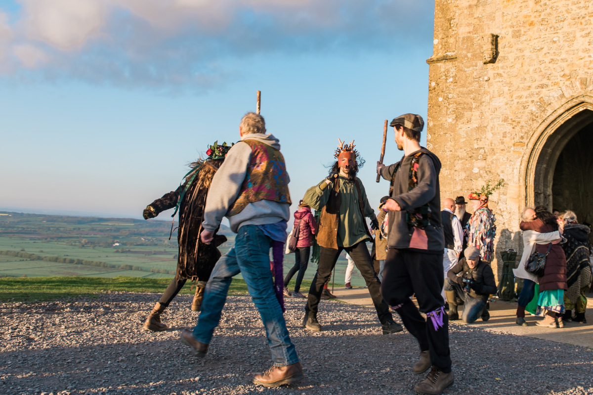 Four dancers in front of Glastonbury tor.