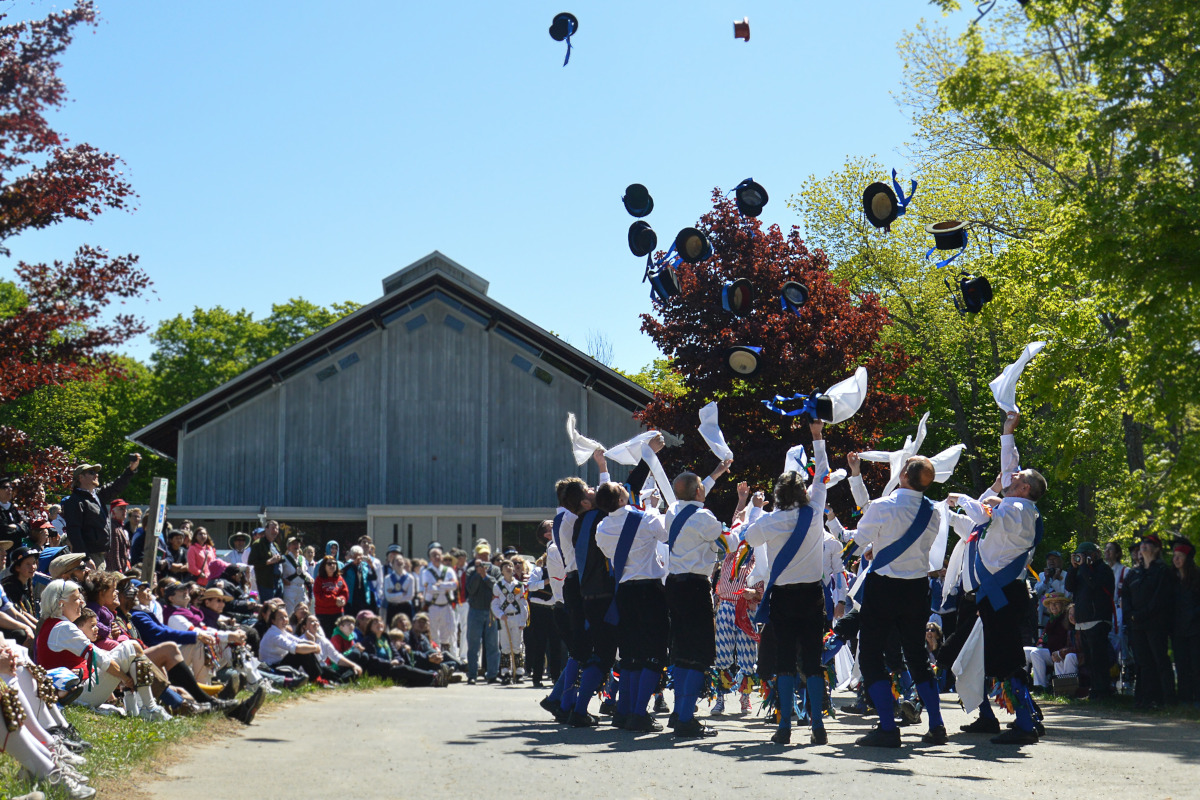 A group of dancers in black and whitr costumes throwing their hats into the air.