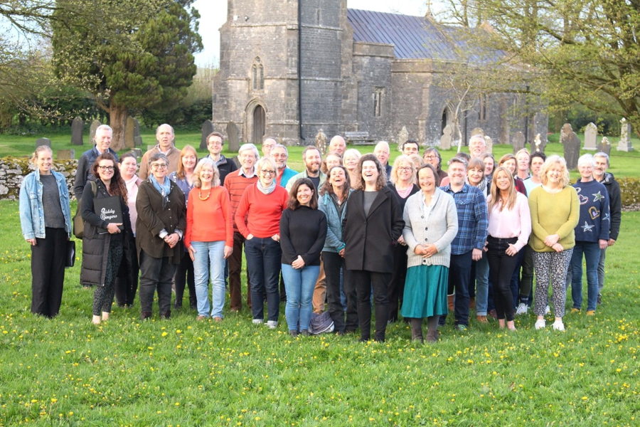 A group of people standing on the grass in front of a church.