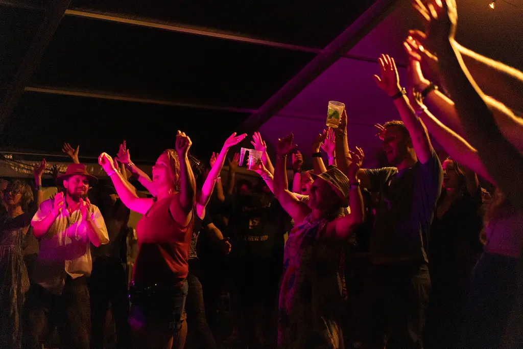 People raising their hands and smiling.